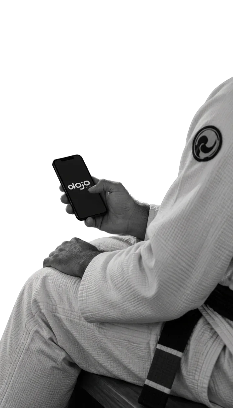 Praticante de jiu-jitsu de quimono segura um celular com o DojoEasy aberto